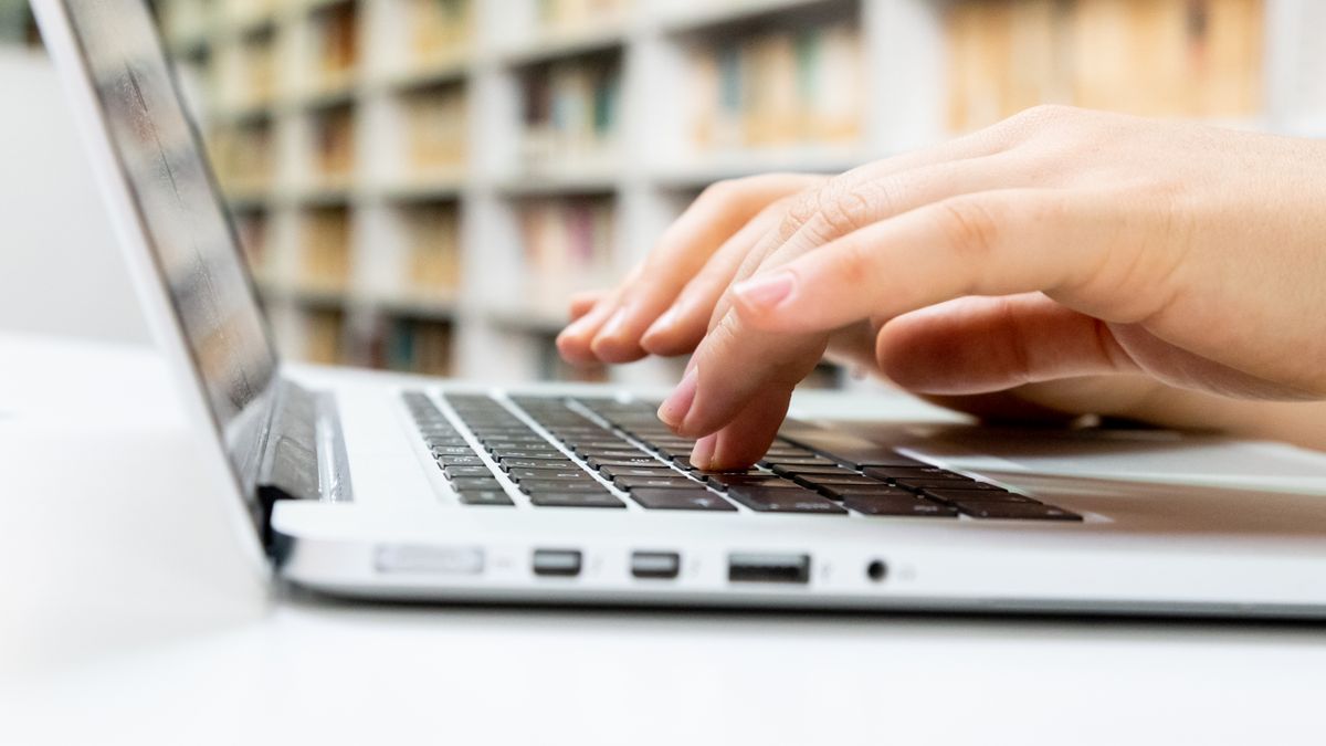 A laptop screen showing a short, focused cold email being drafted, with a browser tab open to the recipient company's LinkedIn profile for research.