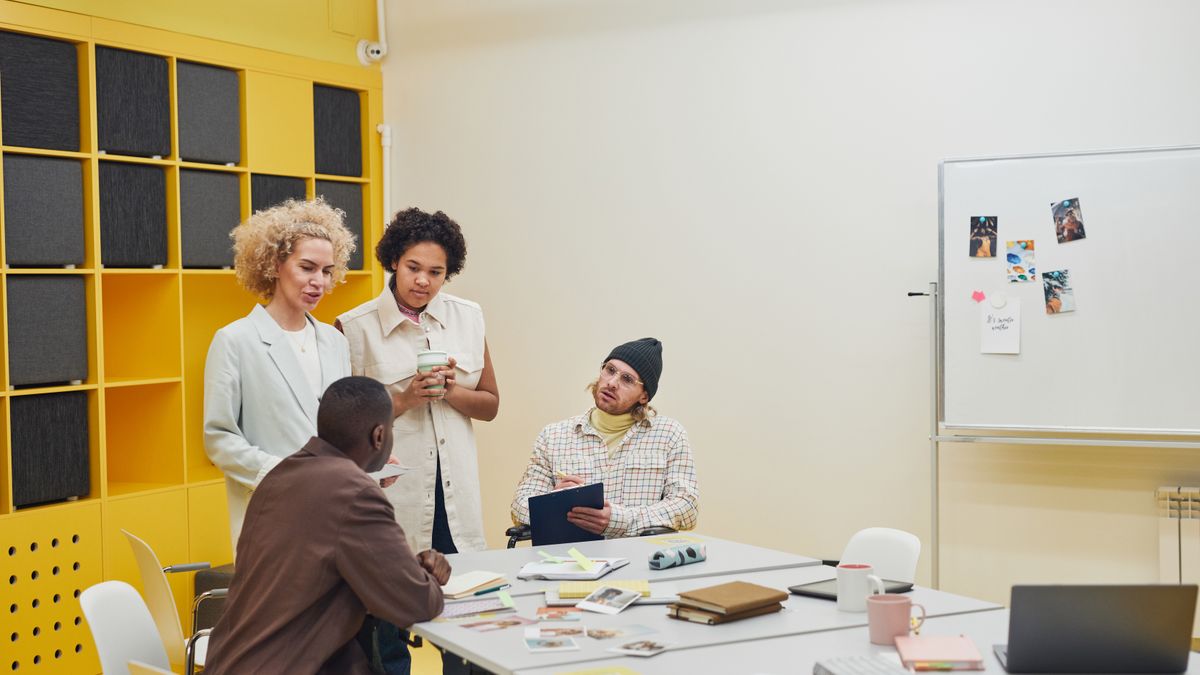 A small team gathered around a table with notes and a whiteboard at a project kickoff meeting, representing onboarding a new Claude Code client.