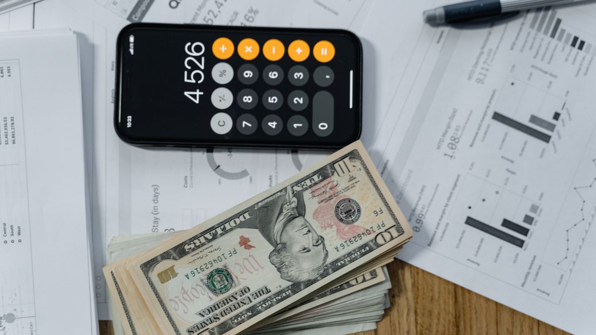 Cash beside a calculator and financial reports on a desk, representing revenue builders leave uncollected.
